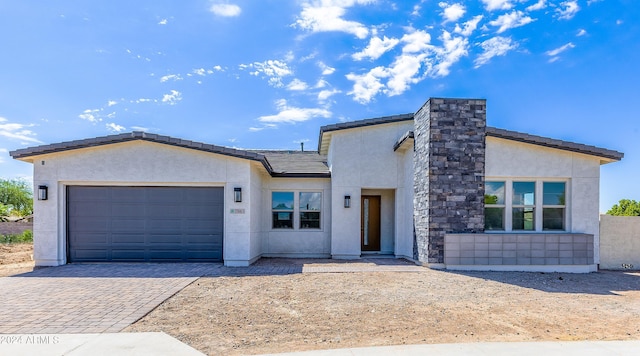 contemporary home featuring a tiled roof, stucco siding, driveway, and a garage