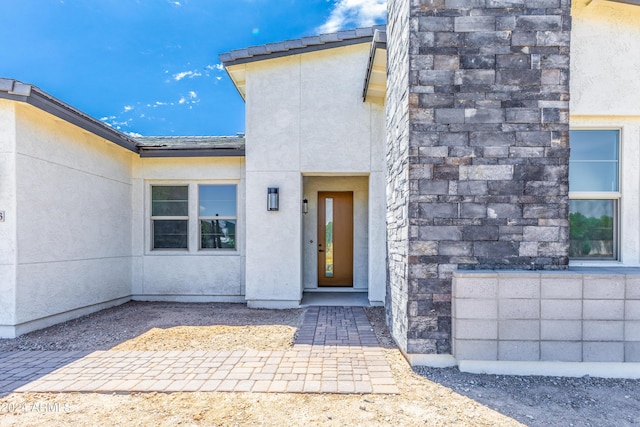 view of exterior entry with stone siding and stucco siding