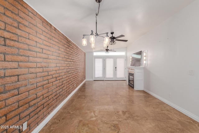 interior space with baseboards, stone finish flooring, and brick wall