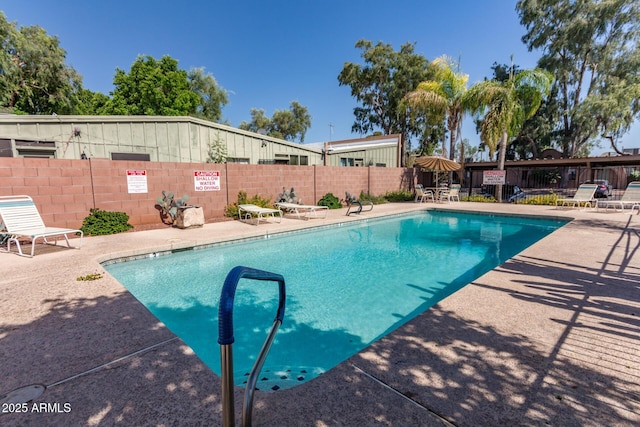 community pool with a patio area and fence