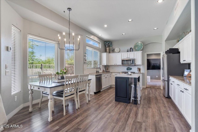 kitchen with an inviting chandelier, white cabinetry, appliances with stainless steel finishes, and a healthy amount of sunlight