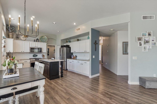 kitchen featuring visible vents, open shelves, decorative backsplash, and appliances with stainless steel finishes