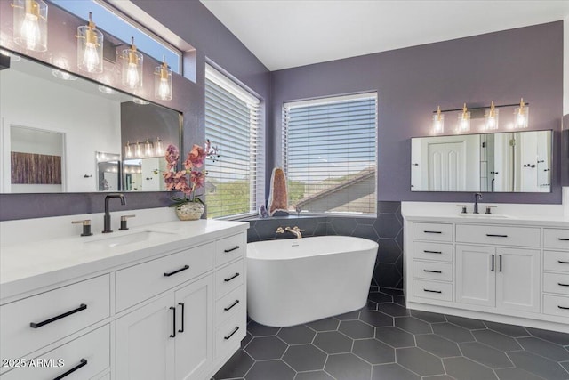 full bath with a sink, a freestanding bath, tile patterned floors, and two vanities