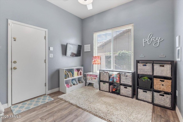 recreation room featuring a ceiling fan, baseboards, and wood finished floors