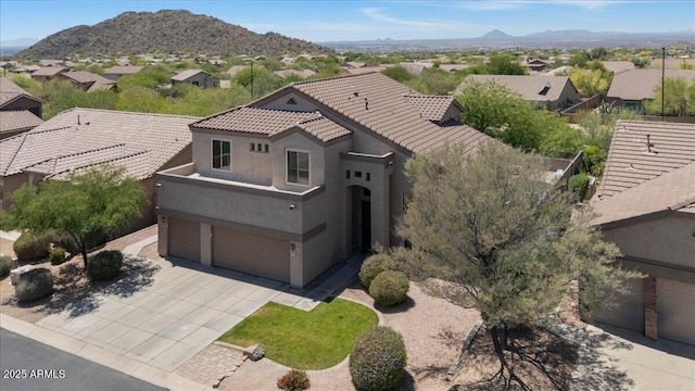 view of front of home featuring a tiled roof, driveway, a residential view, a garage, and stucco siding