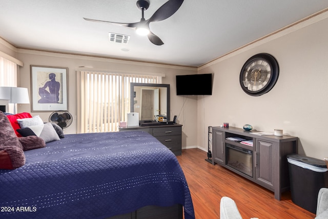 bedroom with light hardwood / wood-style floors, crown molding, and ceiling fan