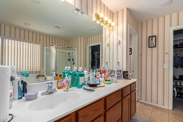 bathroom featuring tile patterned flooring, an enclosed shower, and vanity