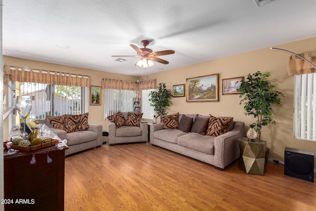 living room with hardwood / wood-style flooring, ceiling fan, and a textured ceiling