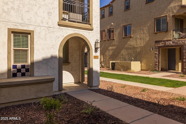 entrance to property featuring a balcony and stucco siding