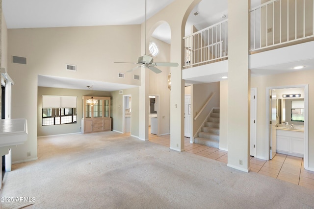 1338 E Greenway Cir, Mesa, AZ 85203 - unfurnished living room featuring healthy amount of natural light, carpet floors, a high ceiling, stairs, and tile patterned flooring
