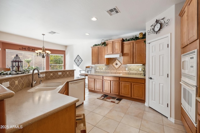 kitchen with sink, white appliances, light tile patterned floors, hanging light fixtures, and backsplash