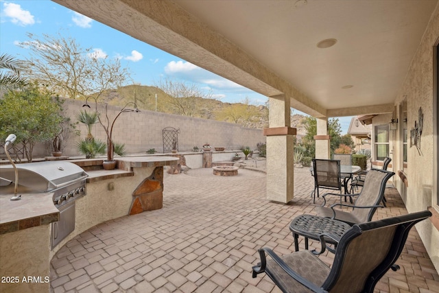 view of patio with an outdoor kitchen, area for grilling, and a fire pit