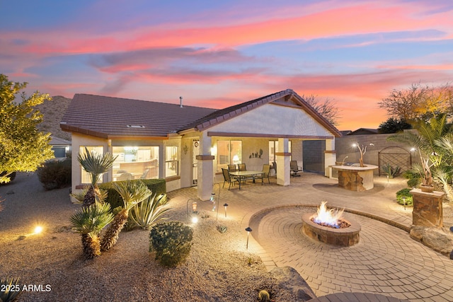 back house at dusk with a patio area and an outdoor fire pit