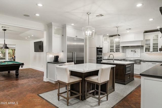 5112 N 41st St, Phoenix, AZ 85018 - kitchen with built in appliances, a kitchen island with sink, brick floors, decorative backsplash, and recessed lighting
