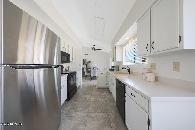 kitchen with white cabinetry, a sink, light countertops, black appliances, and vaulted ceiling