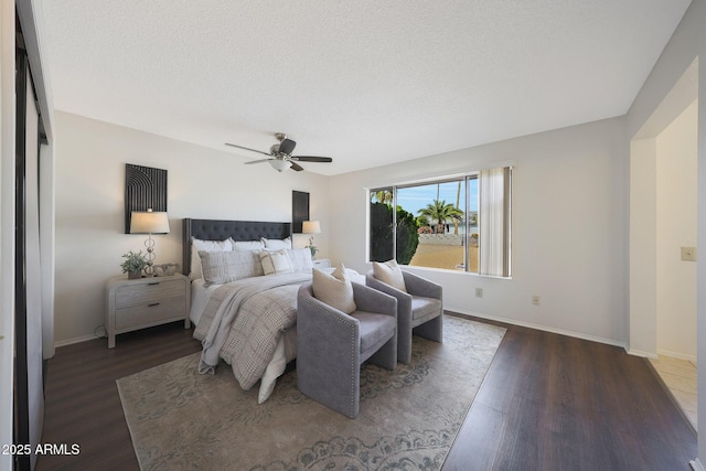 bedroom featuring dark wood-style floors, a ceiling fan, a textured ceiling, and baseboards