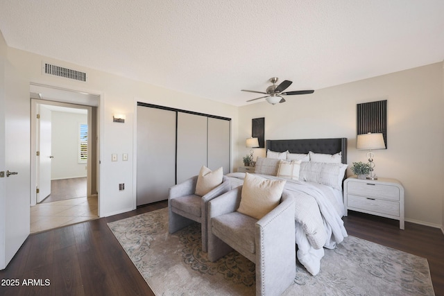 bedroom featuring wood finished floors, a closet, ceiling fan, baseboards, and visible vents