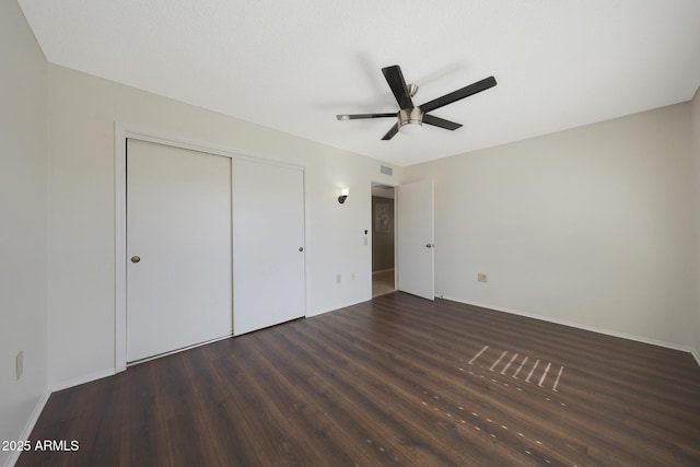 unfurnished bedroom featuring baseboards, wood finished floors, and a closet