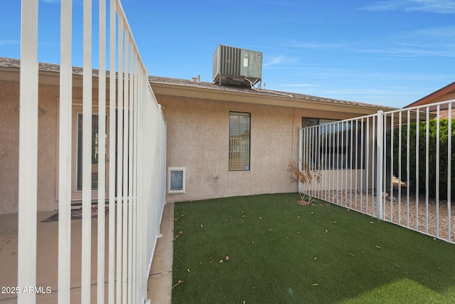 exterior space featuring fence, cooling unit, and stucco siding
