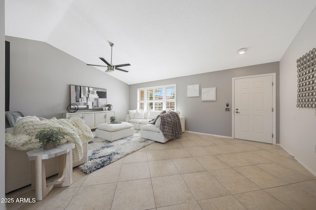 living room with light tile patterned floors, a ceiling fan, vaulted ceiling, and baseboards