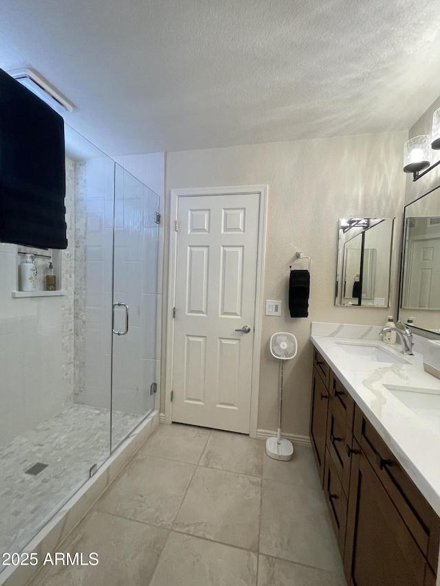 9807 W Mcrae Way, Peoria, AZ 85382 - bathroom featuring a stall shower, a textured ceiling, baseboards, a sink, and double vanity