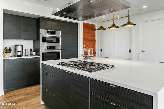 kitchen featuring pendant lighting, light wood-type flooring, stainless steel appliances, and range hood