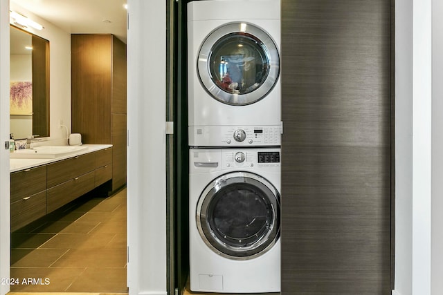 laundry room with stacked washing maching and dryer, sink, and light tile patterned floors