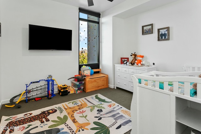 bedroom with dark colored carpet, ceiling fan, floor to ceiling windows, and a nursery area