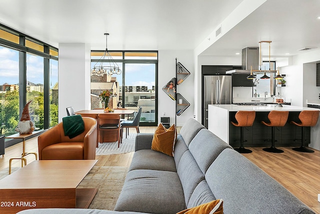 living room featuring light hardwood / wood-style flooring, an inviting chandelier, and a wall of windows