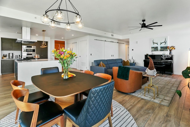 dining area with light hardwood / wood-style floors and ceiling fan with notable chandelier