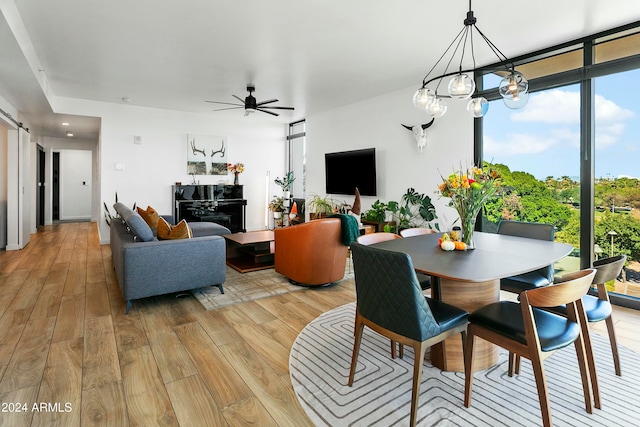 dining area with ceiling fan, expansive windows, and light wood-type flooring