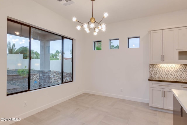 unfurnished dining area with light tile patterned flooring and an inviting chandelier