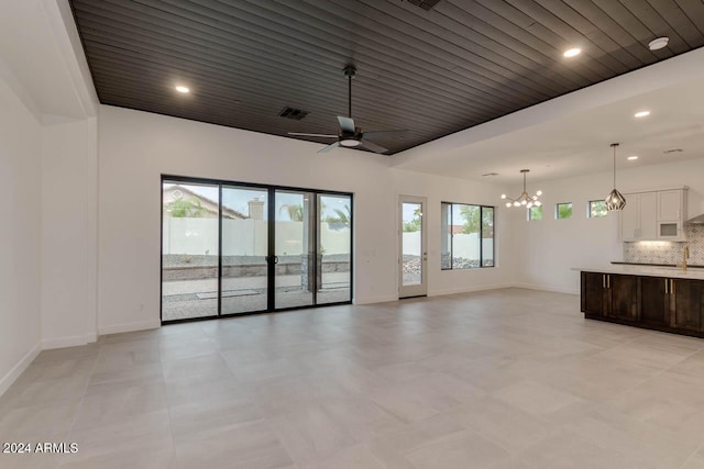 unfurnished living room with sink and ceiling fan with notable chandelier