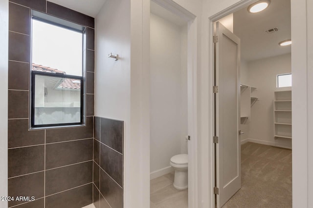 bathroom featuring a tile shower and toilet