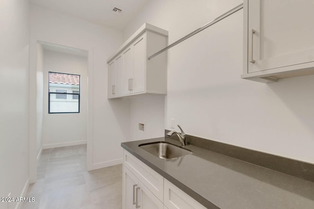 kitchen with white cabinetry, light tile patterned floors, and sink