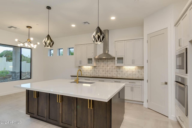 kitchen with stainless steel appliances, wall chimney range hood, sink, and a wealth of natural light