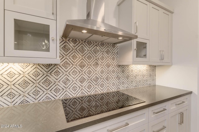 kitchen featuring wall chimney exhaust hood, white cabinets, and backsplash