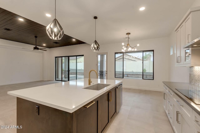 kitchen with hanging light fixtures, white cabinetry, a kitchen island with sink, black electric stovetop, and sink