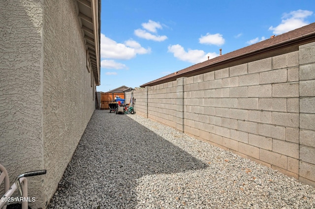 view of side of property with a fenced backyard and stucco siding