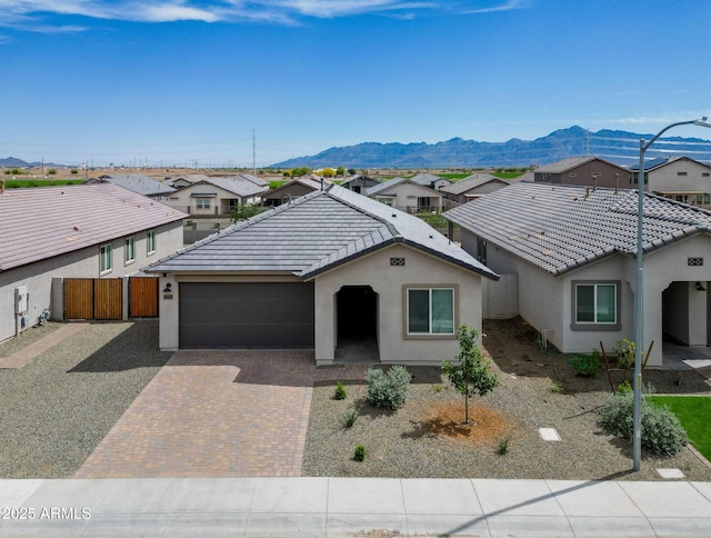 ranch-style house featuring stucco siding, decorative driveway, a residential view, and an attached garage
