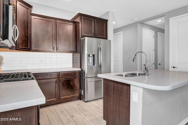 kitchen featuring tasteful backsplash, light wood-type flooring, appliances with stainless steel finishes, and a sink