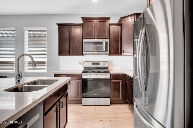 kitchen featuring appliances with stainless steel finishes, dark brown cabinets, backsplash, and a sink