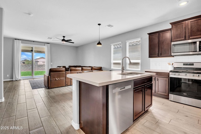 kitchen with light wood-style floors, appliances with stainless steel finishes, light countertops, a sink, and visible vents
