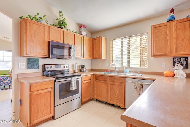 kitchen with sink, light tile patterned flooring, vaulted ceiling, and appliances with stainless steel finishes