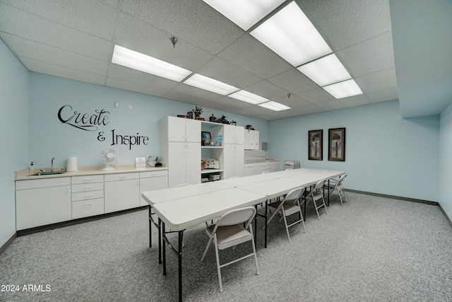 carpeted dining room featuring a paneled ceiling and sink