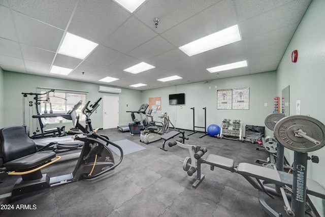 gym featuring a drop ceiling and an AC wall unit