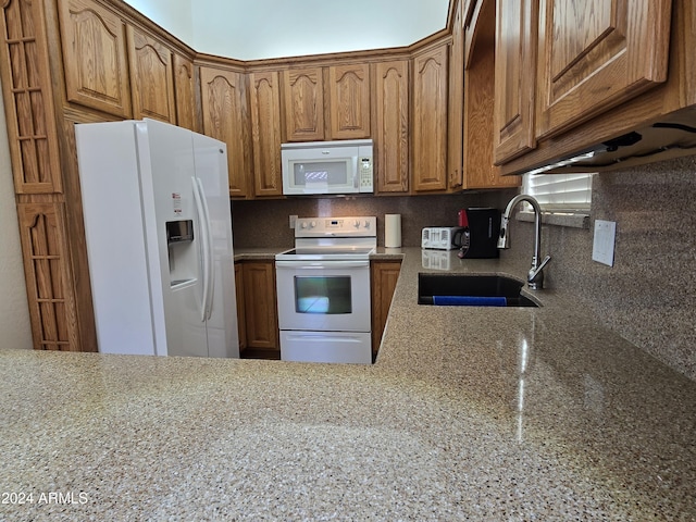 kitchen featuring tasteful backsplash, light stone countertops, sink, and white appliances