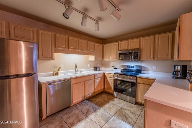 kitchen with appliances with stainless steel finishes, light brown cabinets, rail lighting, and sink