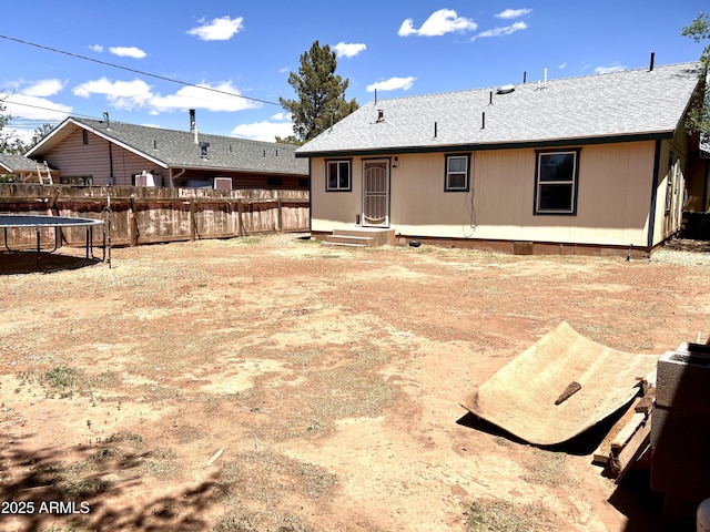 709 W Maple St, Winslow, AZ 86047 - rear view of property with a trampoline, fence, and a shingled roof