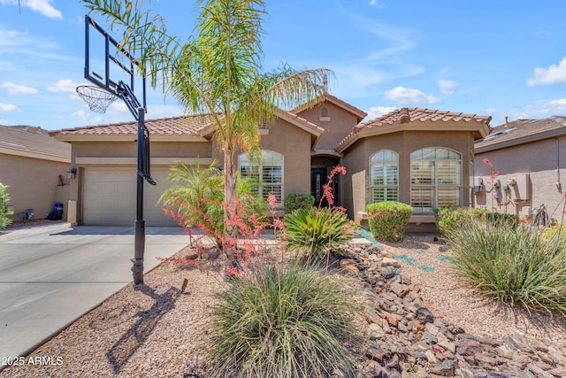 mediterranean / spanish house with a garage, stucco siding, a tiled roof, and driveway